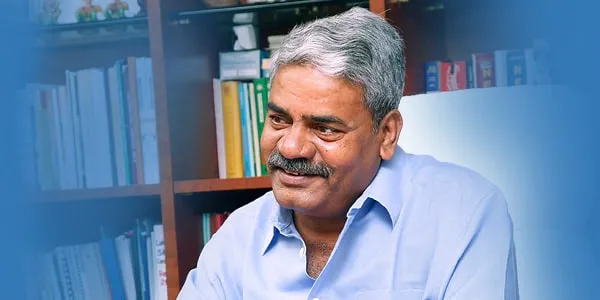 Shivajirao Adhalrao Patil smiling in front of a bookshelf