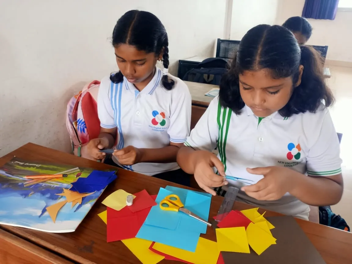 Two students cutting coloured paper for a craft project