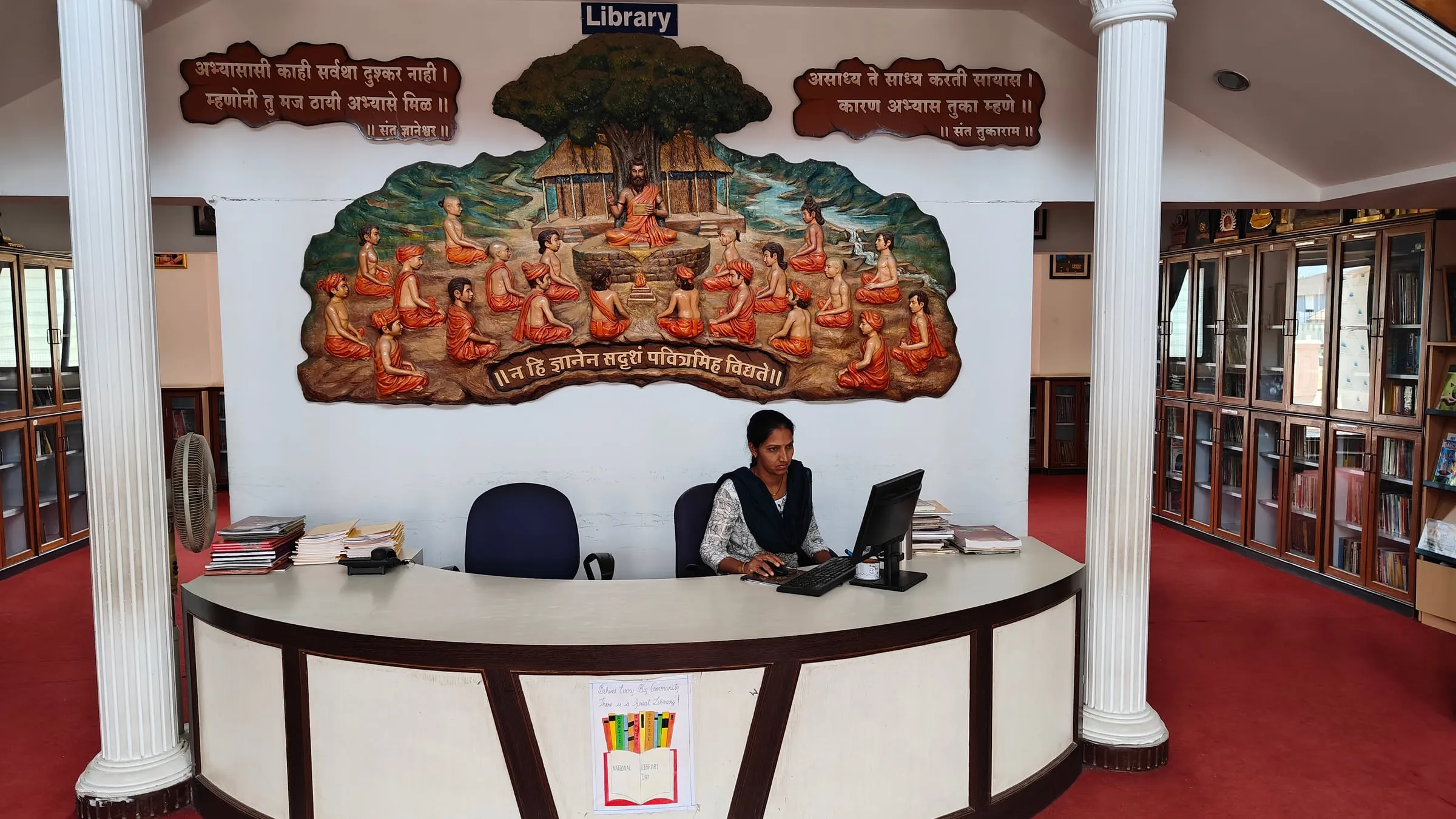 The library desk under a carved mural, with bookshelves on both sides