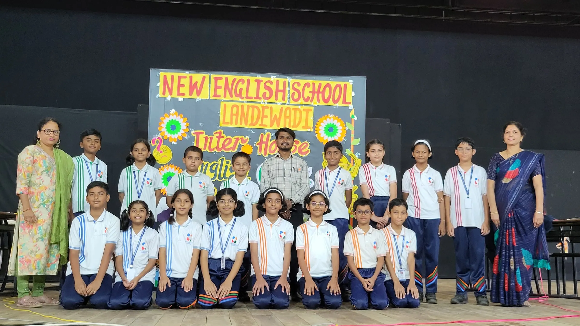 New English School students and teachers in front of an inter-house quiz banner