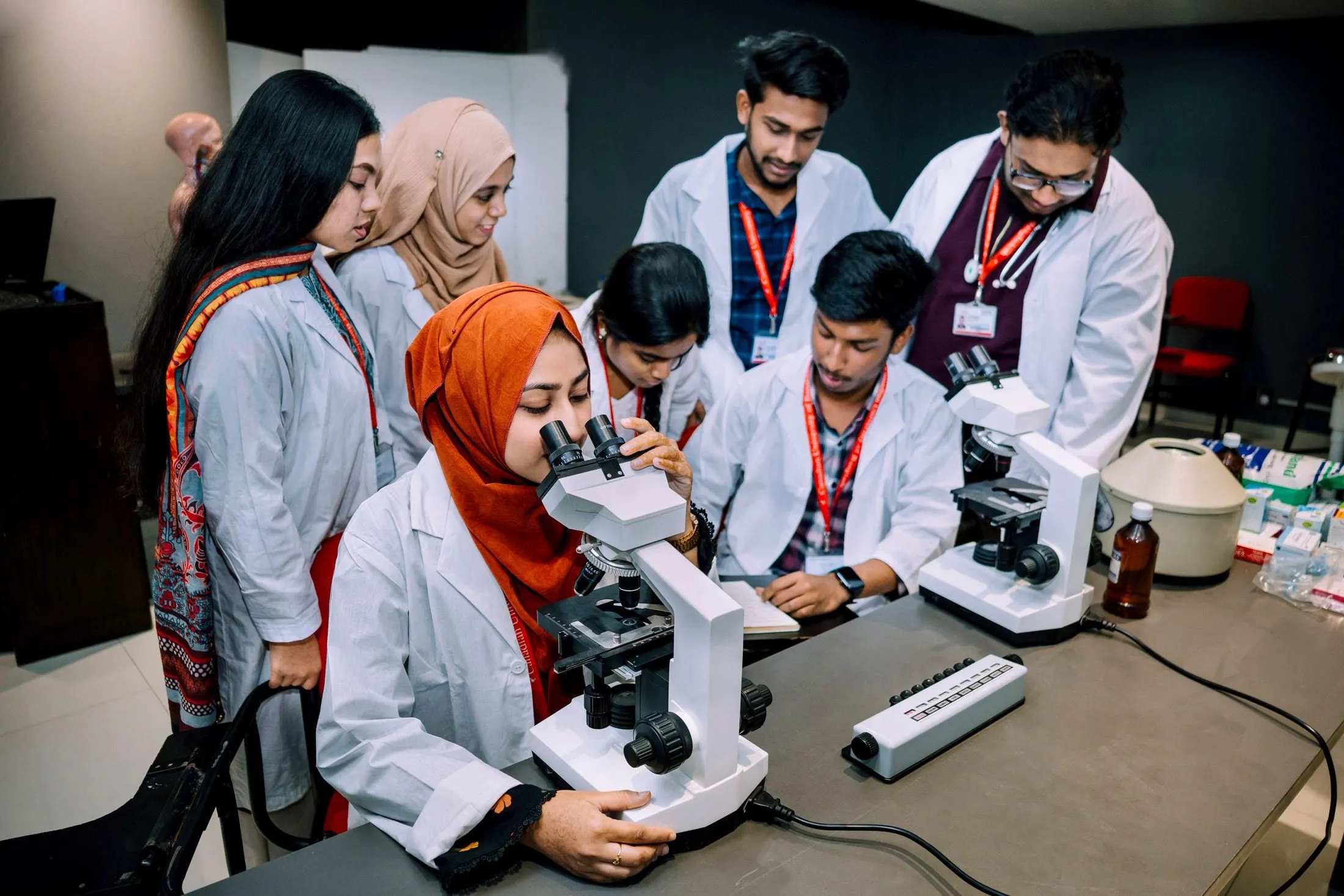 Students in lab coats working at microscopes