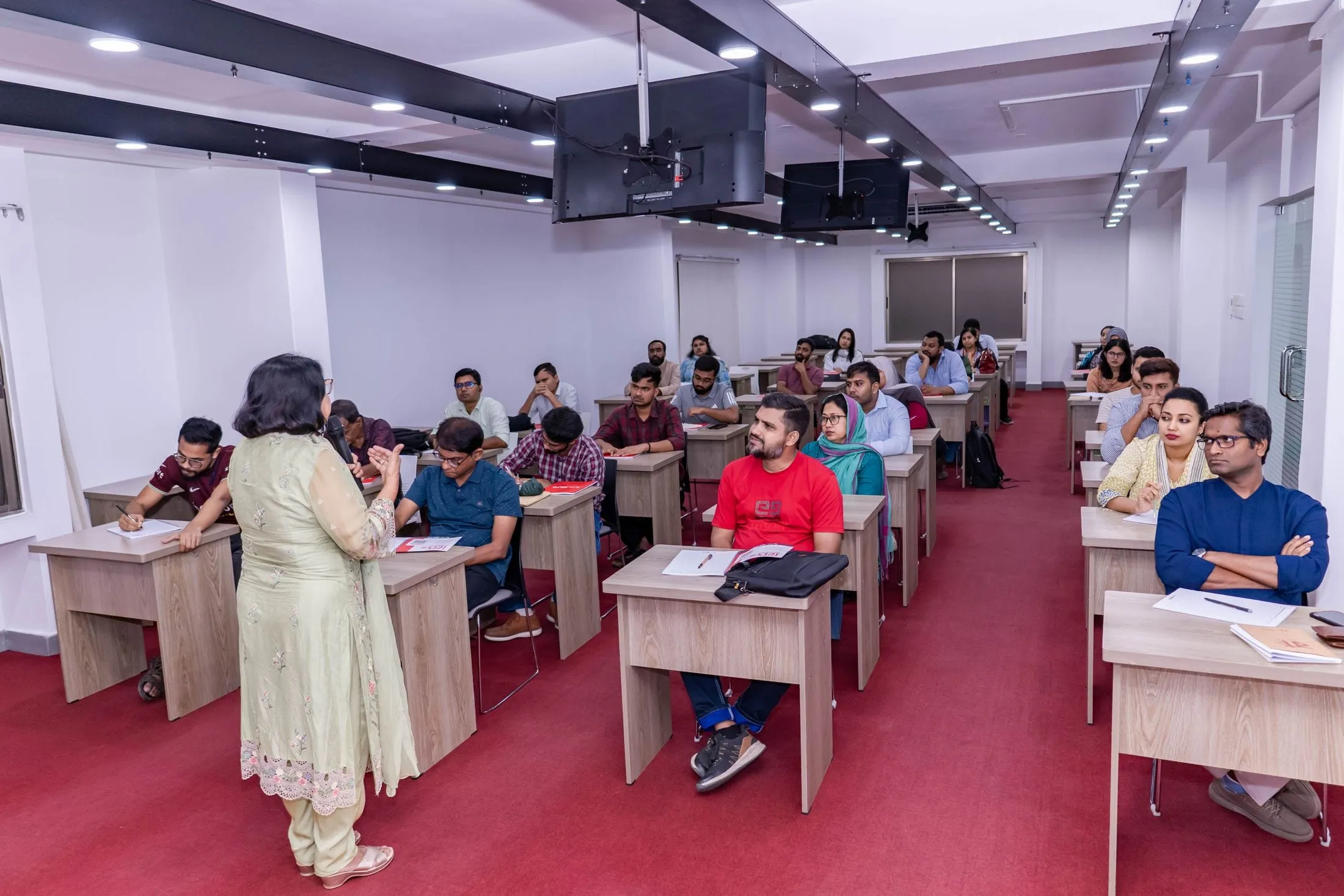 A teacher in a sari teaching a class of adult students
